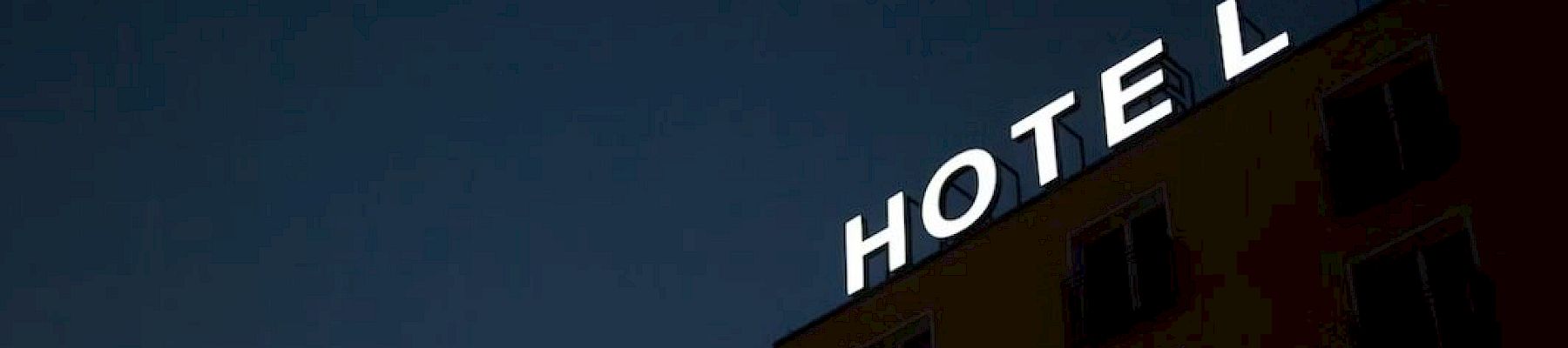The image shows a building at night with a partially lit sign reading "HOTE L," indicating it's a hotel.
