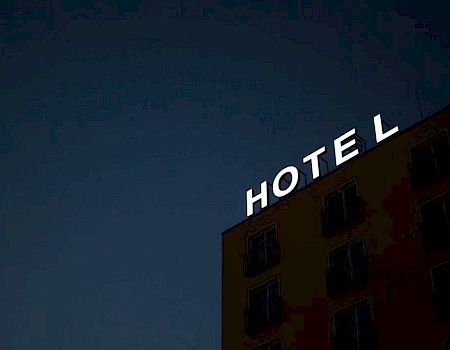 The image shows a building at night with a partially lit sign reading "HOTE L," indicating it's a hotel.