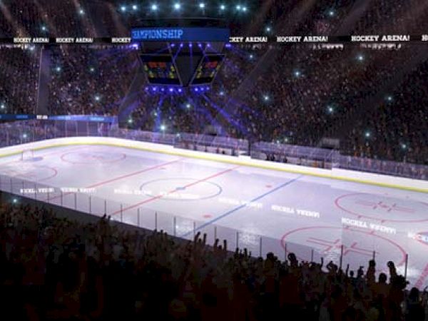 An illuminated ice hockey rink in a crowded arena with fans, spotlights, and banners. The scoreboard is showing, and the atmosphere is lively.