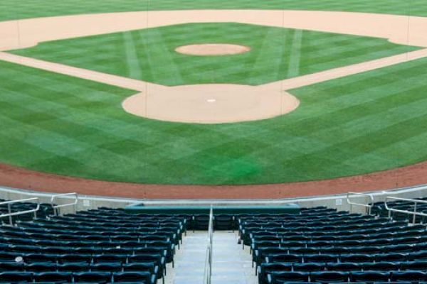 A view of an empty baseball field from the stands, featuring perfectly manicured grass, the diamond, and surrounding seating areas.