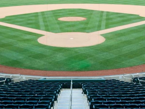 A view of an empty baseball field from the stands, featuring perfectly manicured grass, the diamond, and surrounding seating areas.